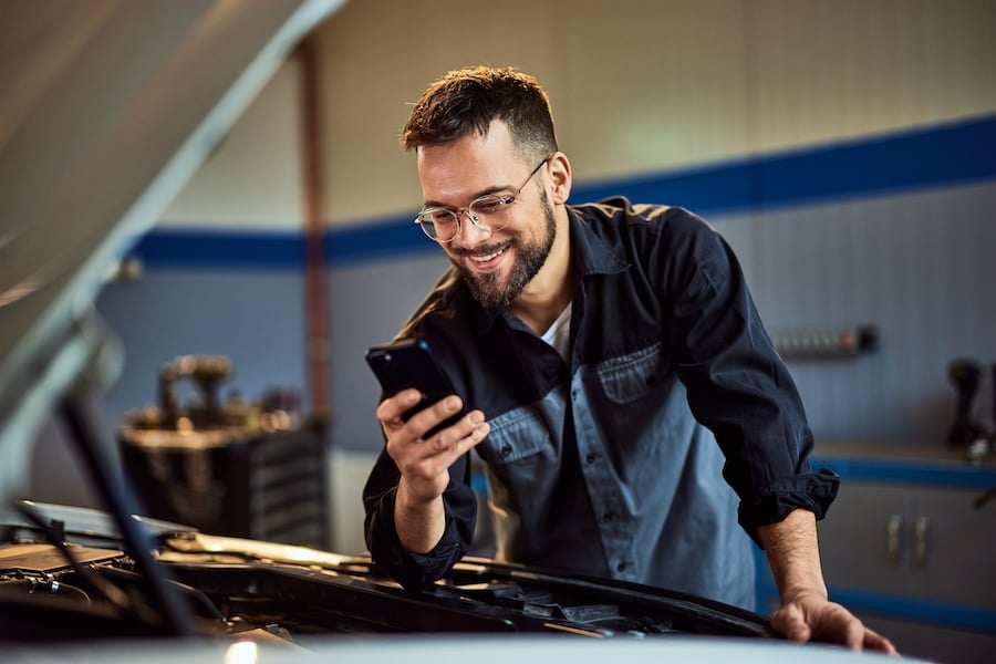 Smiling Car Worker looking at his phone